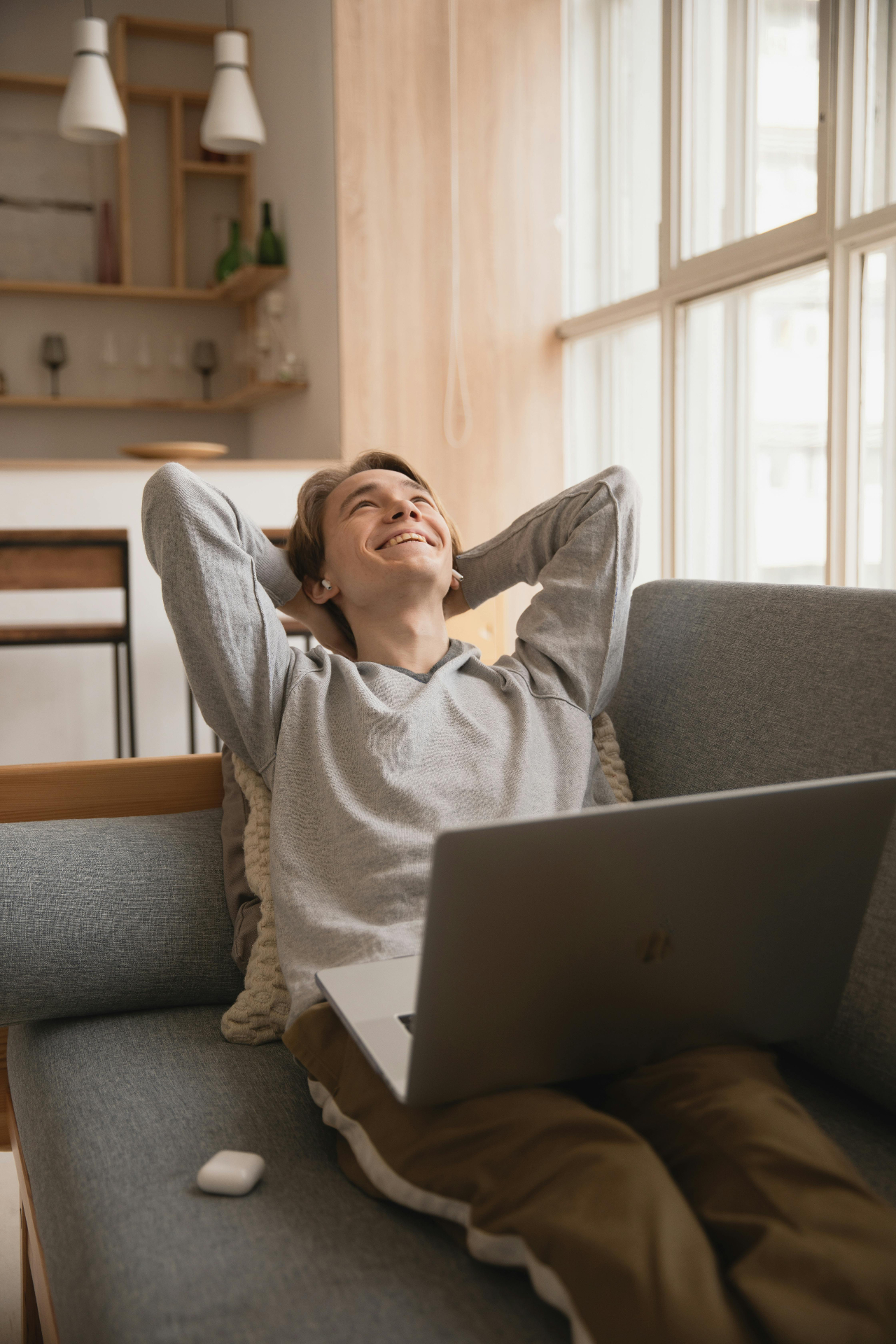 Relaxed homeowner smiling on couch with laptop